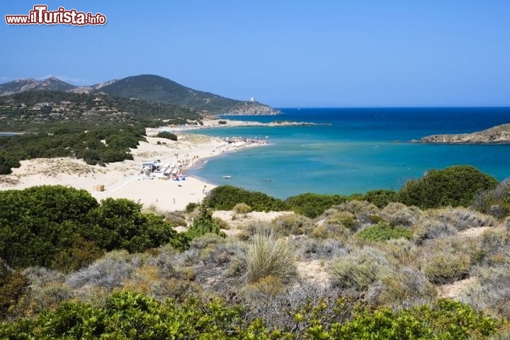 La spiaggia di Su Giudeu nella baia di Chia, in Sardegna - La spiaggia di su Giudeo prende il nome dall’omonimo scoglio che affiora al largo, nell’acqua turchese e trasparentissima della Sardegna meridionale, in provincia di Cagliari. A sua volta lo scoglio – che può essere raggiunto a nuoto o a piedi, in una zona di acqua bassa - si chiama così per la presenza del polpo, che spesso nuota nei paraggi e si rintana negli anfratti della roccia. Una volta arrivati a Su Giudeo arrampicatevi sul sasso, alto 18 metri, e ammirate la distesa d’acqua e cielo che avrete intorno: vi lascerà senza parole. Insieme alle spiagge di S’Acqua Durci, Porto Campana e Colonia, Su Giudeo è una delle famose spiagge che formano la Baia di Chia, ampia e avvolgente, dal fondale sabbioso, ideale per i bambini ma anche per chi ama le lunghe nuotate e lo snorkeling. Alle spalle dell’arenile un affascinante paesaggio di dune.
Per raggiungere la spiaggia di Su Giudeo percorrete in auto la Strada Statale panoramica 195 e seguite le indicazioni: la spiaggia si trova sulla sinistra. In alta stagione il parcheggio è a pagamento - © Elisa Locci / Shutterstock.com