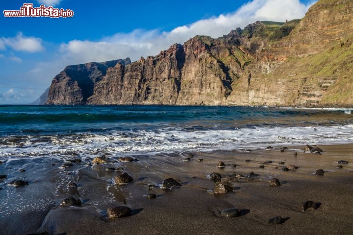 Le Acantilados de Los Gigantes a Tenerife, Spagna - Lungo la costa occidentale di Tenerife (Canarie, Spagna) si innalzano le Acantilados de los Gigantes, ovvero “le scogliere dei giganti”. Il nome dice già molto: questa immensa parete rocciosa, quasi verticale, sfiora un’altezza massima di circa 600 metri, e a picco sulle onde crea una scenografica muraglia naturale che ruba a chiunque si avvicini uno sguardo ammirato. Lunghe ben 10 km, le scogliere sono la continuazione della catena montuosa di Teno, e all’interno di un’ampia insenatura ospitano la pittoresca località portuale di Los Gigantes. In paese potrete osservare le scogliere in tutta la loro bellezza dalla Playa de Arena, una spiaggetta di sabbia scura di origine vulcanica, oppure dal Puerto Santiago, dove tra l’altro potrete salpare per una bella gita in barca. Probabilmente incontrerete qualche balena o qualche delfino.
Le Acantilados de los Gigantes fanno parte del Parque Rural del Teno e si trovano a 130 km da Santa Cruz: per raggiungerle si prende la strada TF-5 fino al Puerte de la Cruz, si prosegue lungo la TF-820 fino a Santiago del Teide, quindi si continua sulla TF-436 fino a Masca. Da qui parte un sentiero di media difficoltà che conduce alla spiaggia incastonata tra le scogliere  - © ZM_Photo / Shutterstock.com
