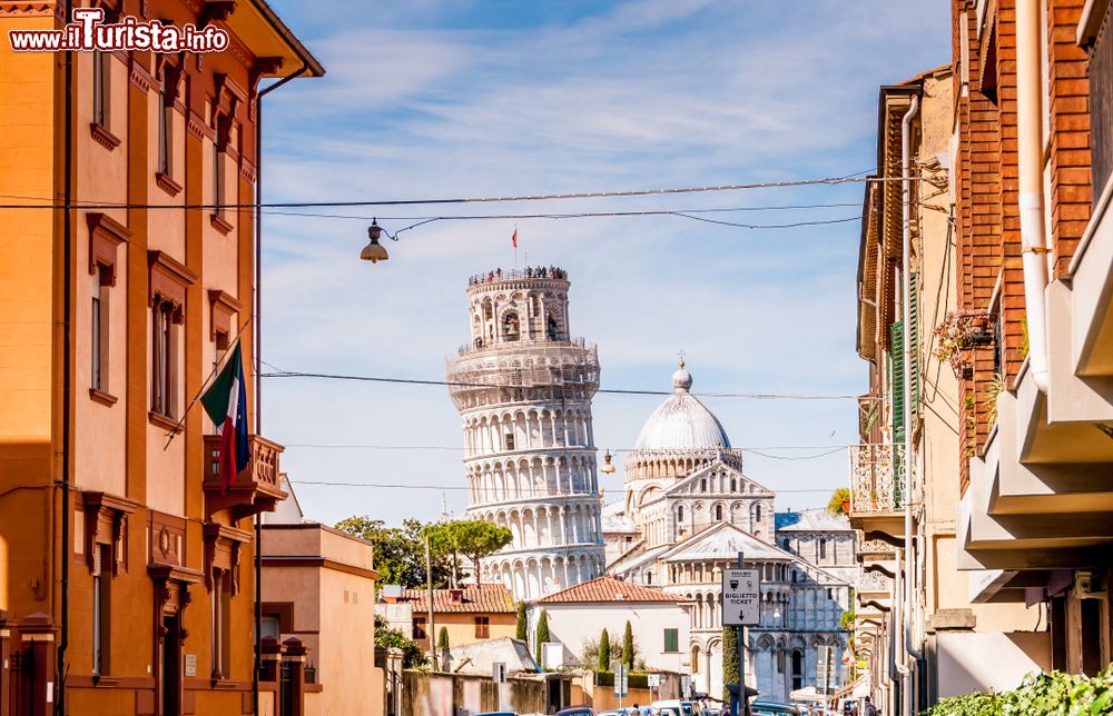 una_strada_del_centro_storico_di_pisa_e_in_prospettiva_il_campanile_e_il_duomo_in_piazza_dei_miracoli